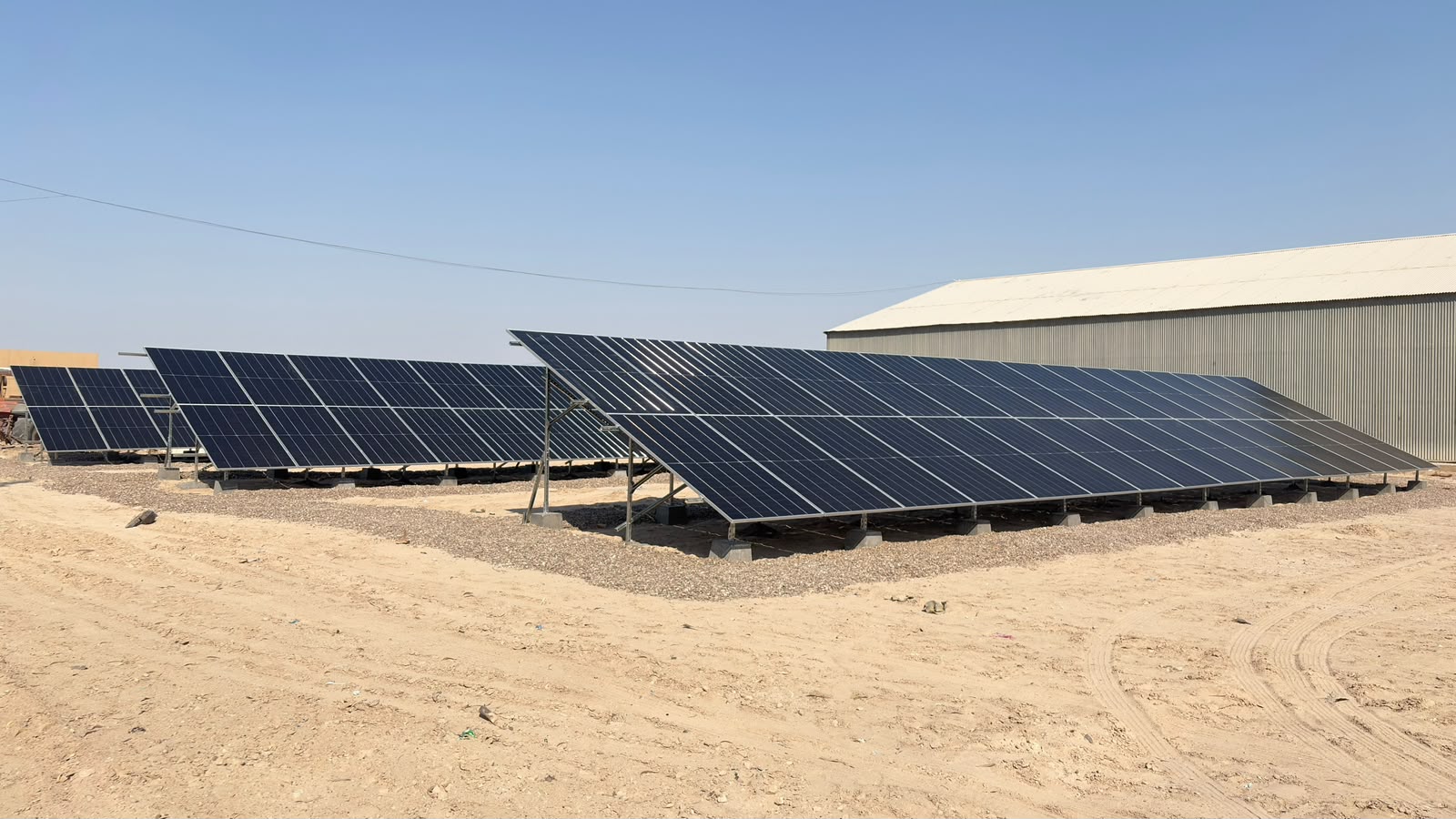 Rows of tilted solar panels fixed on concrete bases at the Abu Ghraib site